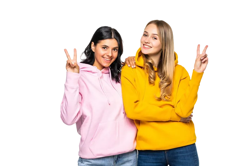 pretty-two-girlfriends-women-showing-v-sign-symbols-wearing-casual-bright-hoodies-jeans-isolated-white-wall